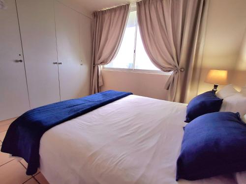 a bedroom with a large white bed with blue pillows at Margate Boulevard Beachfront Apartment in Margate