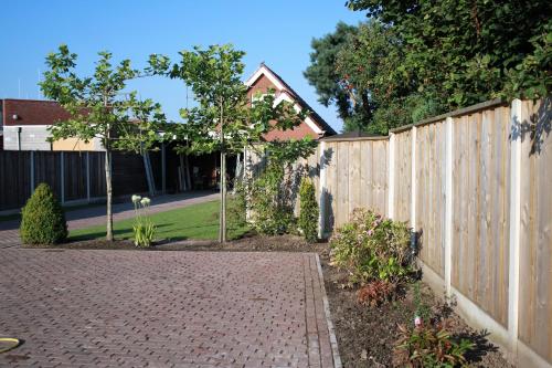 a fence in a yard with a brick driveway at Bed&Breakfast de Hooimoat in Losser