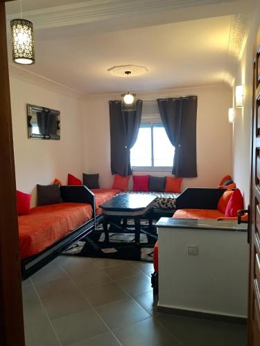 a living room with red couches and a table at Appart Hotel Tanger Paname in Tangier