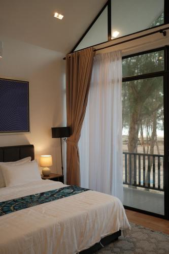 a bedroom with a bed and a large window at Villa Alaya Malai in Setiu