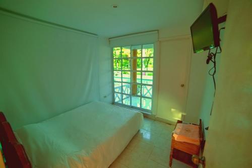 a bedroom with a bed and a window and a television at Hotel - Granja de Animales San Basilio de Palenque in San Basilio del Palenque