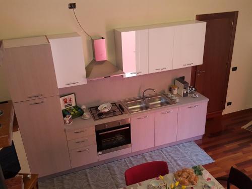 a kitchen with white cabinets and a sink and a table at Dimora di Mara in Santeramo in Colle