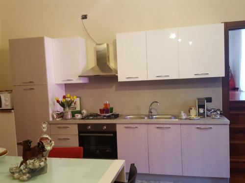 a kitchen with white cabinets and a sink and a table at Dimora di Mara in Santeramo in Colle