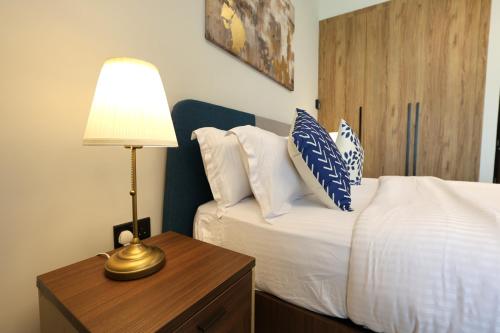 a bedroom with a bed and a table with a lamp at Chic Studio near Cleveland by Central Stay in Abu Dhabi
