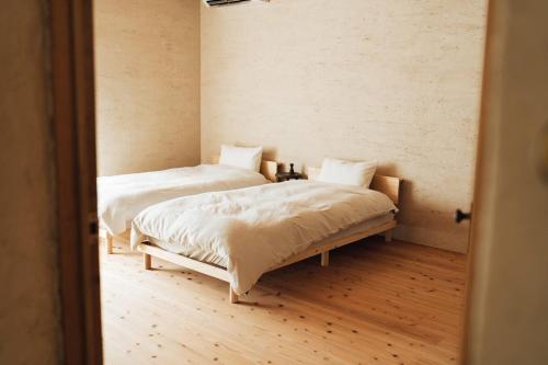 zwei Betten in einem Zimmer mit Holzboden in der Unterkunft 一棟貸しヴィラmatai in Kitsuki