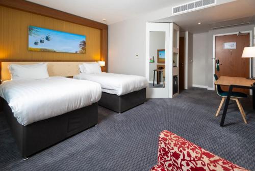 a hotel room with two beds and a desk at Holiday Inn Derby Riverlights by IHG in Derby