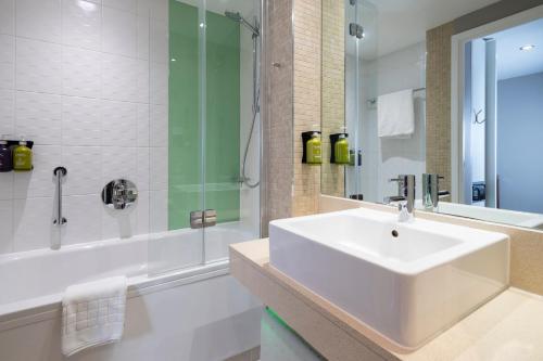 a white bathroom with a sink and a shower at Holiday Inn Derby Riverlights by IHG in Derby