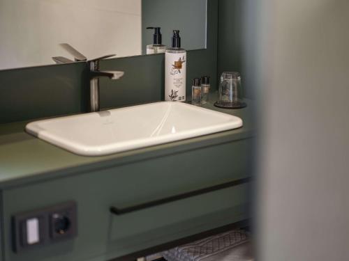 a sink in a bathroom with a green counter at vevio - Hotel & Events in Spiesen-Elversberg