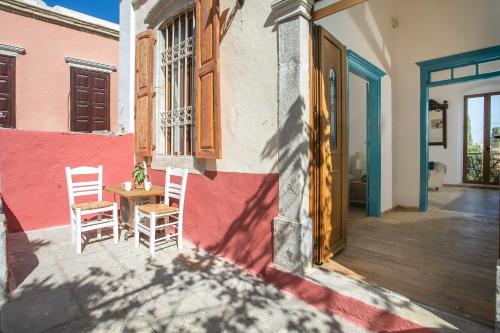 a porch of a house with two chairs and a table at Galini & Serena Apartments in Symi