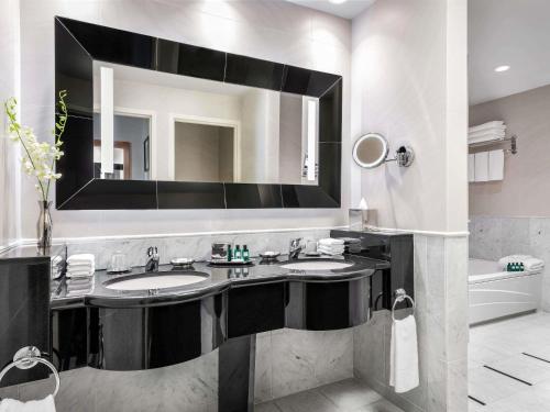 a bathroom with two sinks and a large mirror at Sofitel Montreal Golden Mile in Montréal