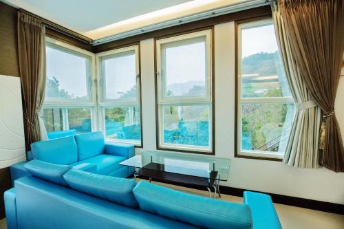 a living room with blue furniture and windows at Natural Residence B&B in Taian