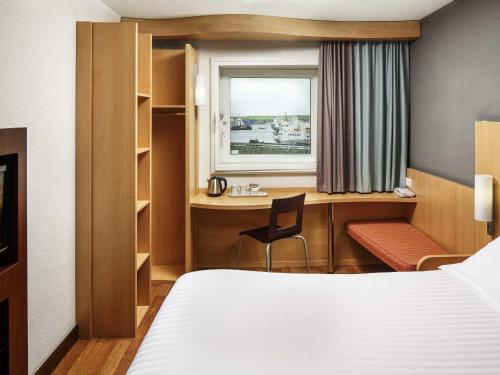 a hotel room with a bed and a desk and a window at ibis Aberdeen Centre – Quayside in Aberdeen