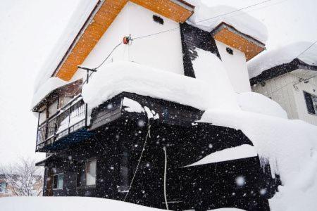 a house covered in snow in front of a house at Happy House in Nozawa Onsen