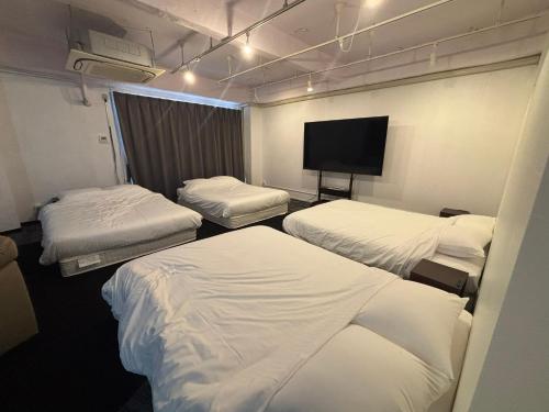 a room with three beds and a flat screen tv at P-STAY広島平和公園withペット 301号室 in Hiroshima