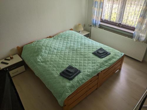 a bedroom with a bed with green comforter and two towels at Ferienwohnung am Park in Greiz