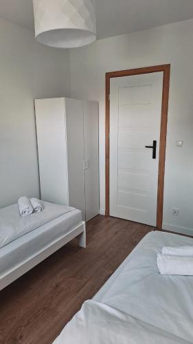 a bedroom with two beds and a white door at Apartament OLIWIA 5 in Nowy Targ