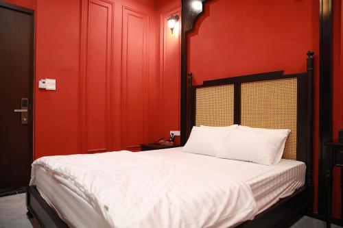 a bedroom with red walls and a bed with white sheets at Gấu Hotel Cầu Giấy in Hanoi