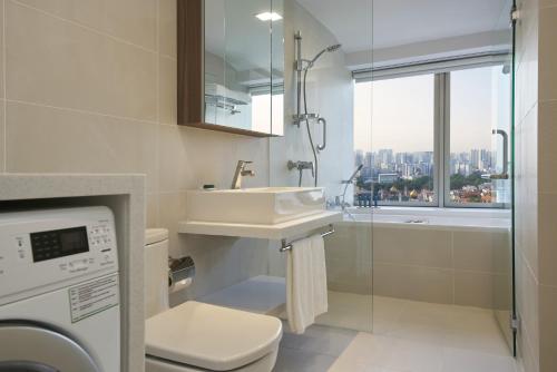 a bathroom with a sink and a shower with a window at PARKROYAL Serviced Suites Singapore in Singapore
