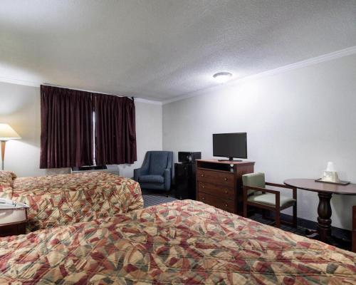 a hotel room with two beds and a desk and a tv at Rodeway Inn Syracuse Carrier Circle in East Syracuse