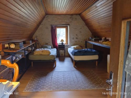 a attic room with two beds and a window at La Chambre Périgourdine in Journiac