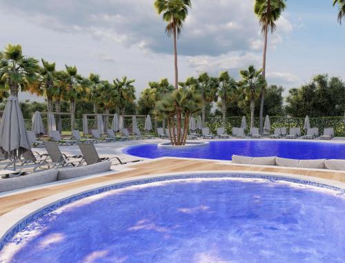 a large swimming pool with chairs and palm trees at Cala Millor Garden Hotel - Adults Only in Cala Millor
