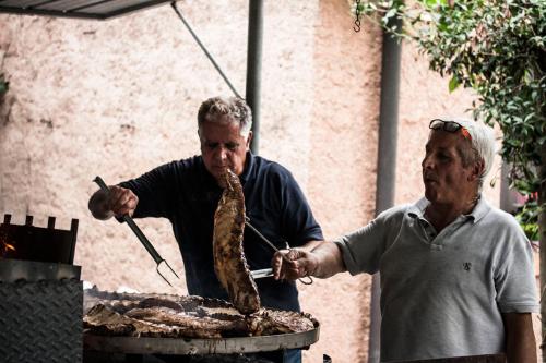 two men are preparing food on a grill with tongs at Agriturismo Villa Mocenigo in Mirano