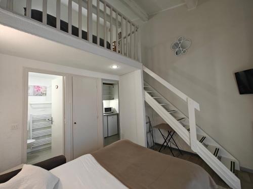 a white bedroom with a staircase and a bed at Auberge Des Pins in Tourrettes