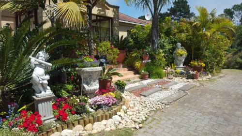 a garden with flowers and statues in front of a house at 110 Bay View in Brenton-on-Sea