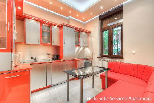 eine Küche mit einem roten Sofa und einem Tisch in der Unterkunft Hello Sofia Guesthouse in Sofia