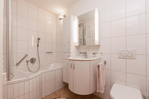 uma casa de banho branca com um lavatório, uma banheira e um WC. em Chesa Derby 3 em Sankt Moritz-Bad