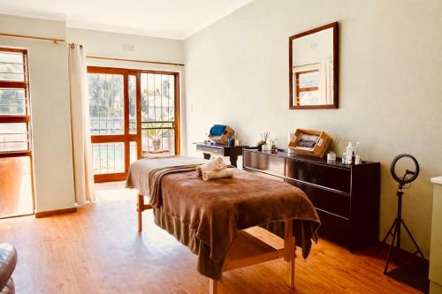 a bedroom with a bed and a dresser with a cat sitting on a table at La Cura Stay in Johannesburg