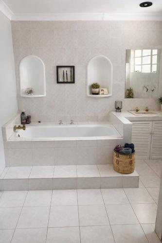 a white bathroom with a tub and a sink at La Cura Stay in Johannesburg