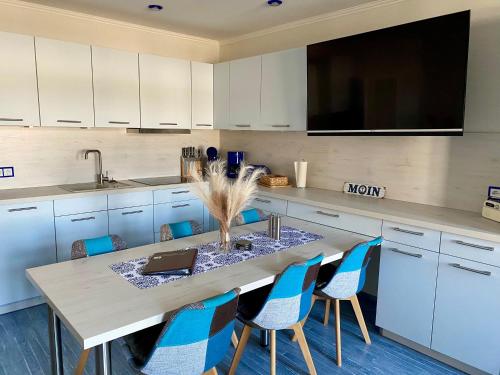 a kitchen with a table with blue chairs and a tv at Kieferneck Ferienwohnung Hedi in Karlshagen