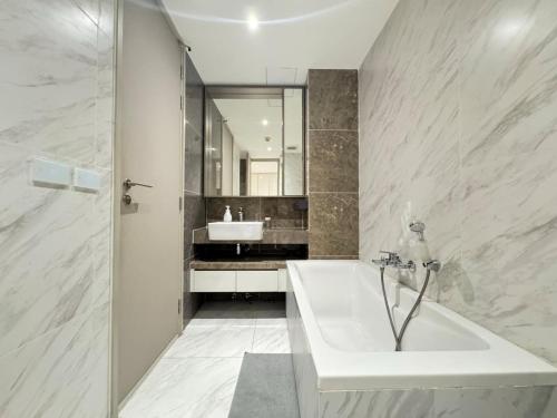 a white bathroom with a tub and a sink at Fynn Bangkok Asoke Condo in Bangkok