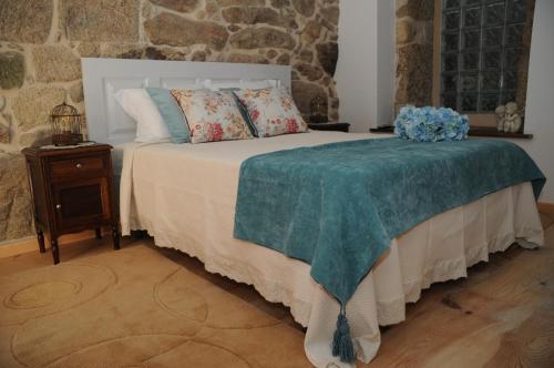 a bedroom with a white bed with a blue flower on it at Casinhas da Levada in Sobredo