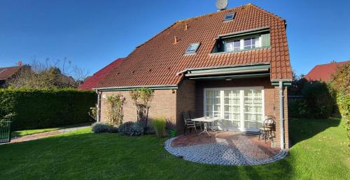 a house with a table and chairs in the yard at lüttje Meerzeithuus in Carolinensiel