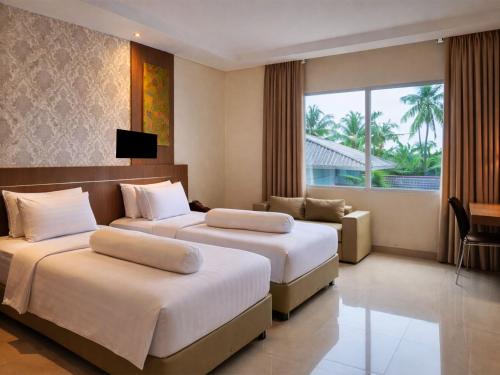 a hotel room with two beds and a couch at Nevada Ketapang Hotel in Ketapang
