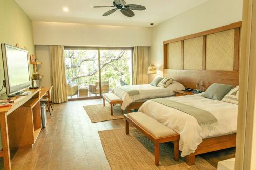 a bedroom with two beds and a flat screen tv at Soul Spring Sanctuary Cuernavaca, WorldHotels Luxury in Xochitepec