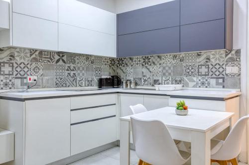 a kitchen with white cabinets and a white table and chairs at Floriana Cozy Haven in Il-Furjana