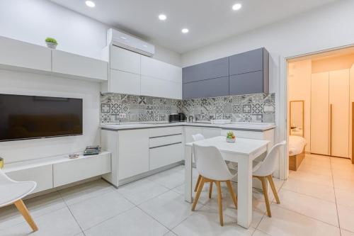 a kitchen with white cabinets and a white table and chairs at Floriana Cozy Haven in Il-Furjana