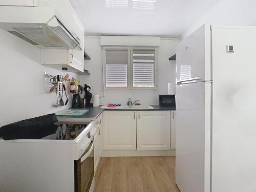 a kitchen with white cabinets and a white refrigerator at Le jardin de Gavrelle, Maison 4 lits, Wifi, jardin in Gavrelle