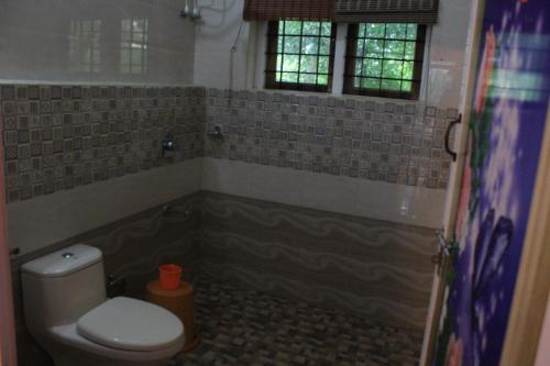 Un baño con inodoro y ventana. en Horn Bill Cottage, en Thekkady