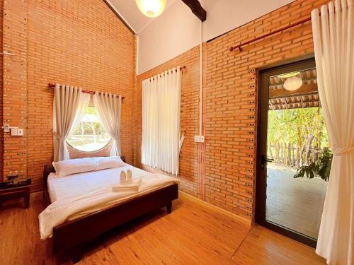 a bedroom with a bed and a brick wall at An Tiên Ecolodge in Tân Phú