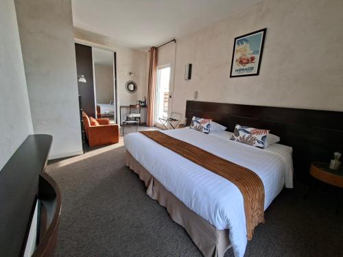a hotel room with a large bed and a chair at Logis Hôtel Synaya in Sanary-sur-Mer