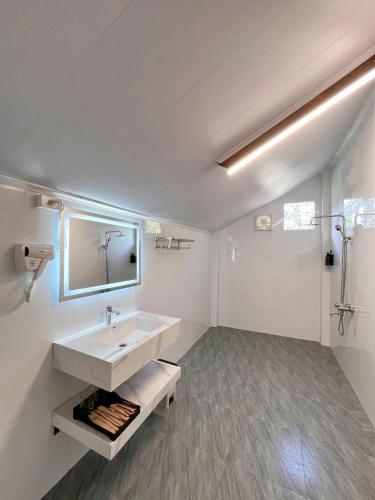a white bathroom with a sink and a shower at An Tiên Ecolodge in Tân Phú