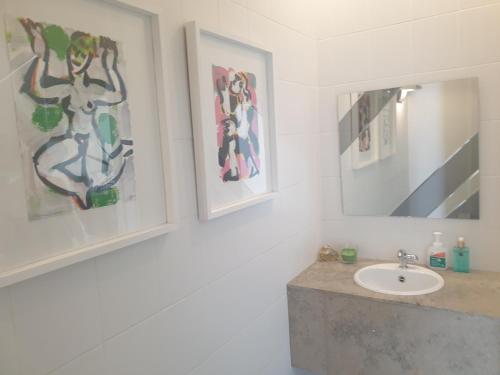 a bathroom with a sink and paintings on the wall at Guesthouse Thibault in Gistel