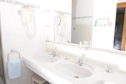 a bathroom with two sinks and a large mirror at Landgasthof Hotel Muhr in Gallbrunn