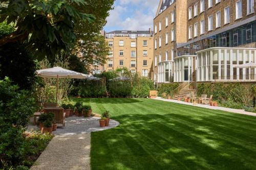 a green yard with benches and an umbrella at Miiro Templeton Garden in London