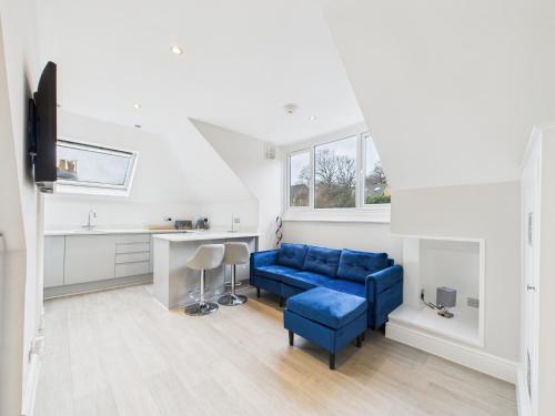 a living room with a blue couch and a kitchen at The loft apartment in Bromley