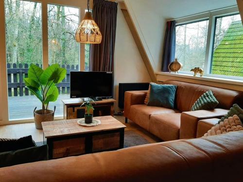 a living room with two couches and a tv at Chalet Het Hulstje 2 in Durbuy